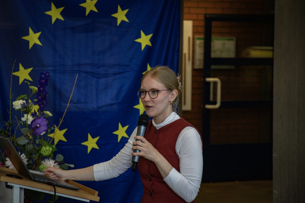 Frau Hoge beim Vortrag; im Hintergrund die Europa-Fahne.